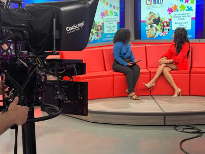 newsroom studio with camera pointing at two ladies on a couch