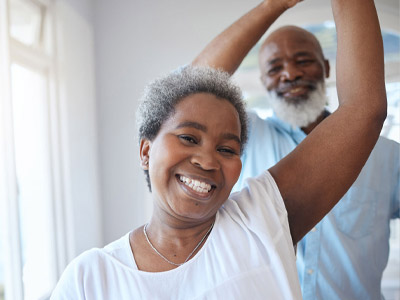 two older adults smiling at the camera while dancing