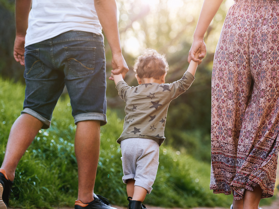 mother and father holding child's hands