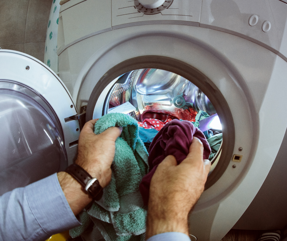 person putting clothes in a washing machine